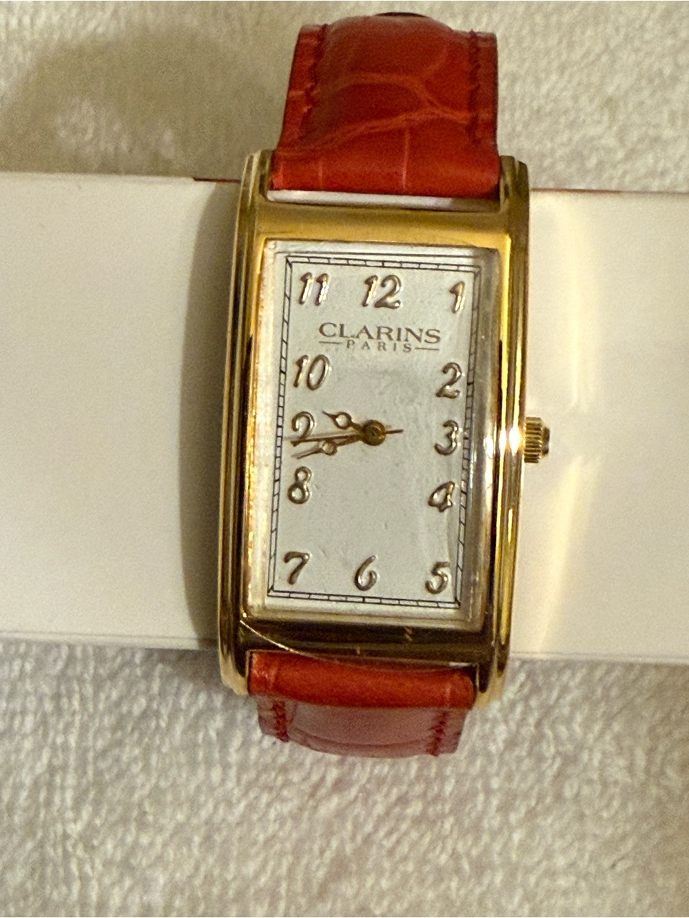 Clarins Gold-Tone Rectangular Watch with Red Strap and White Dial